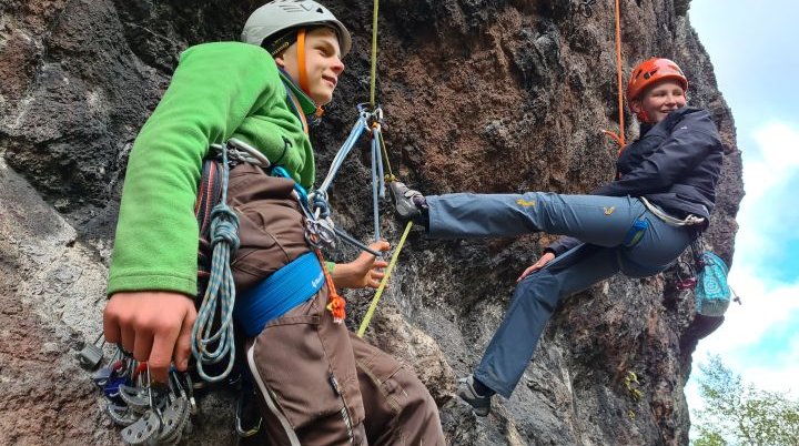 Zwei Kinder hängen am Kletterseil am Fels | © Chris Ulber